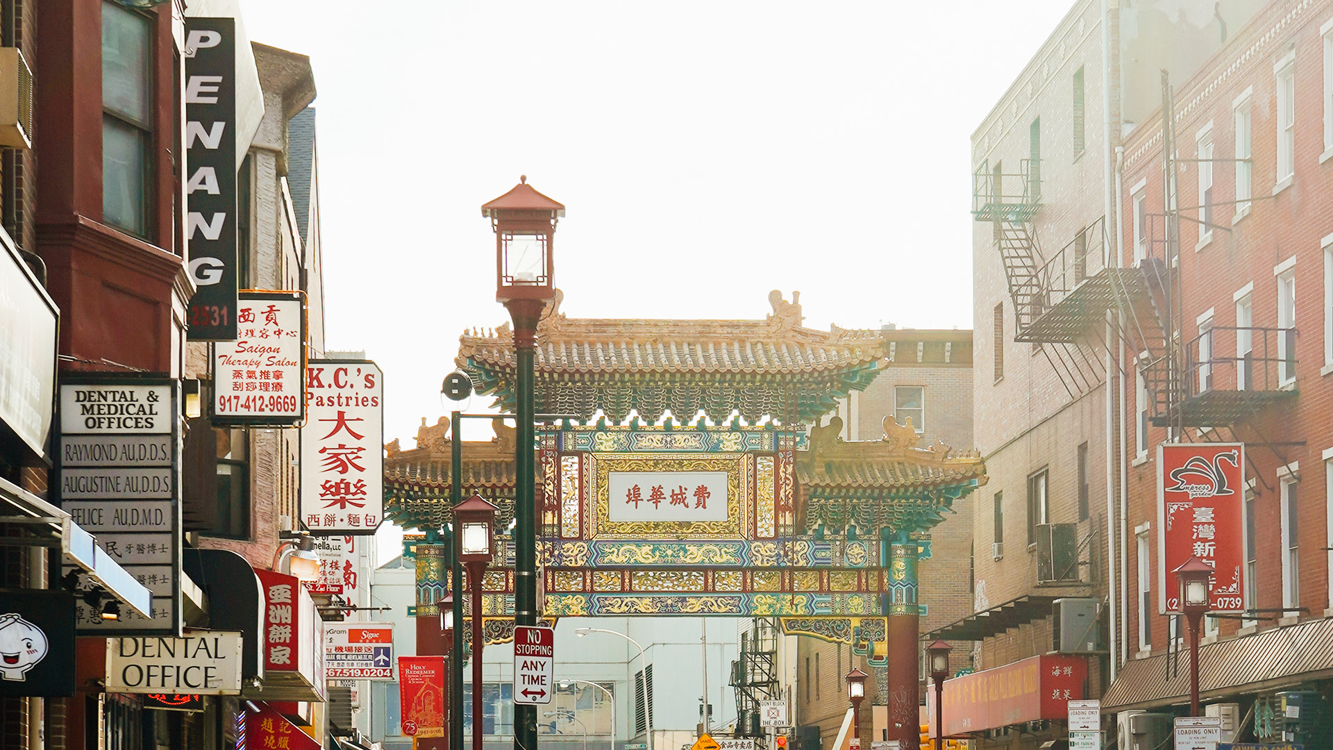 A street in Chinatown with signs for Chinese businesses and a large decorative archway.