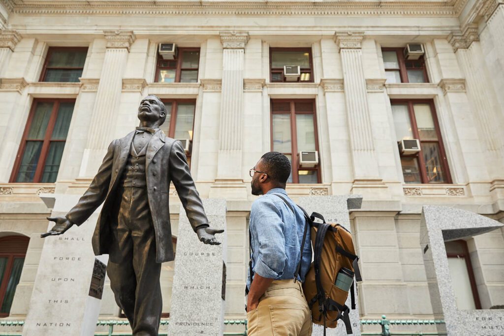 A man views a statue of Octavius Catto.