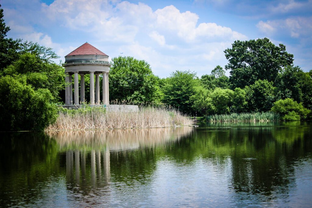 A large gazebo stands tall to the left overlooking a lake with lush greenery surrounding it in the beautiful FDR Park