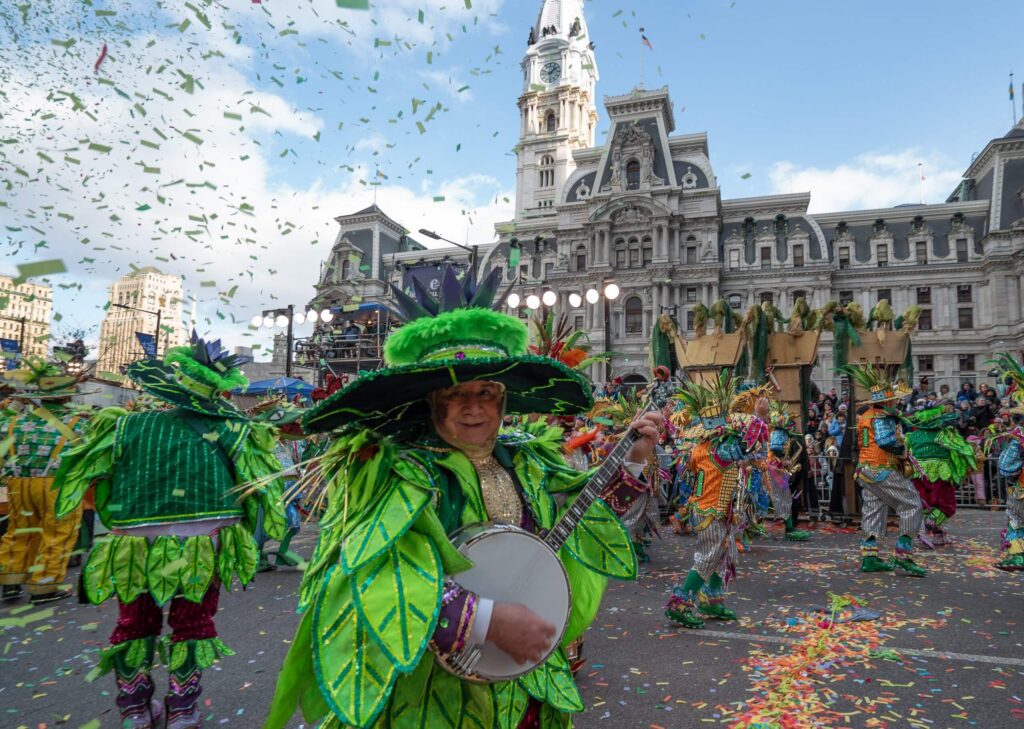 Mummers in neon green costumes play instruments in front of City Hall during the annual Mummers Parade
