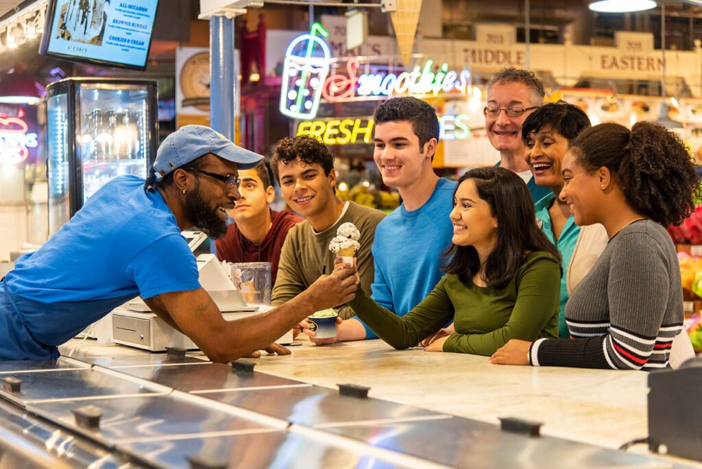 A person handing another person an ice cream.