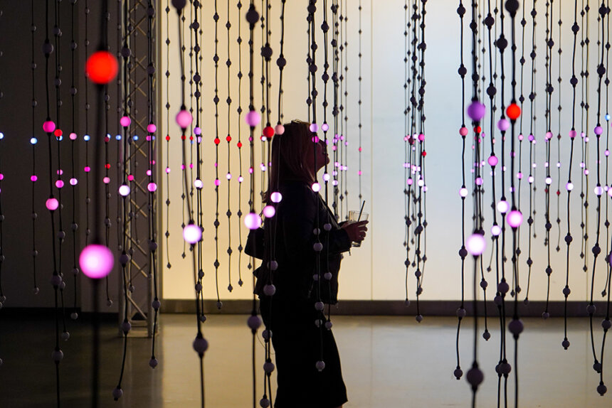 Person walks through a magical room filled with lights hanging from strings at Wonderspaces exhibit in Philadelphia.