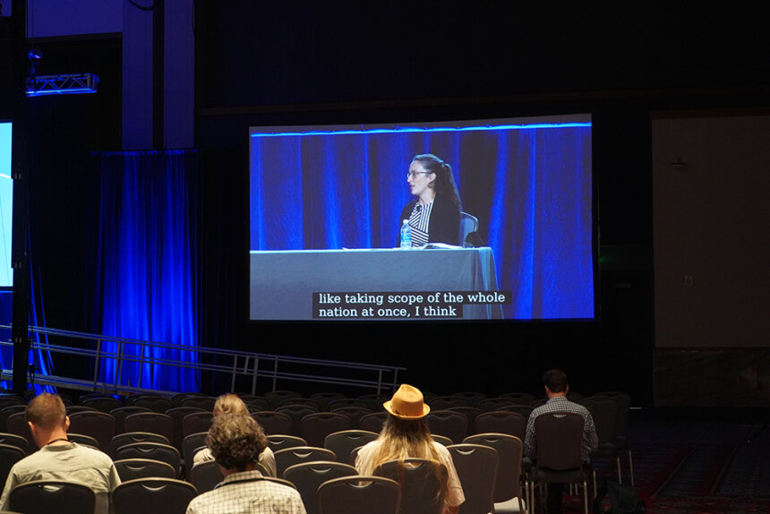 A person speaking on screen with subtitles