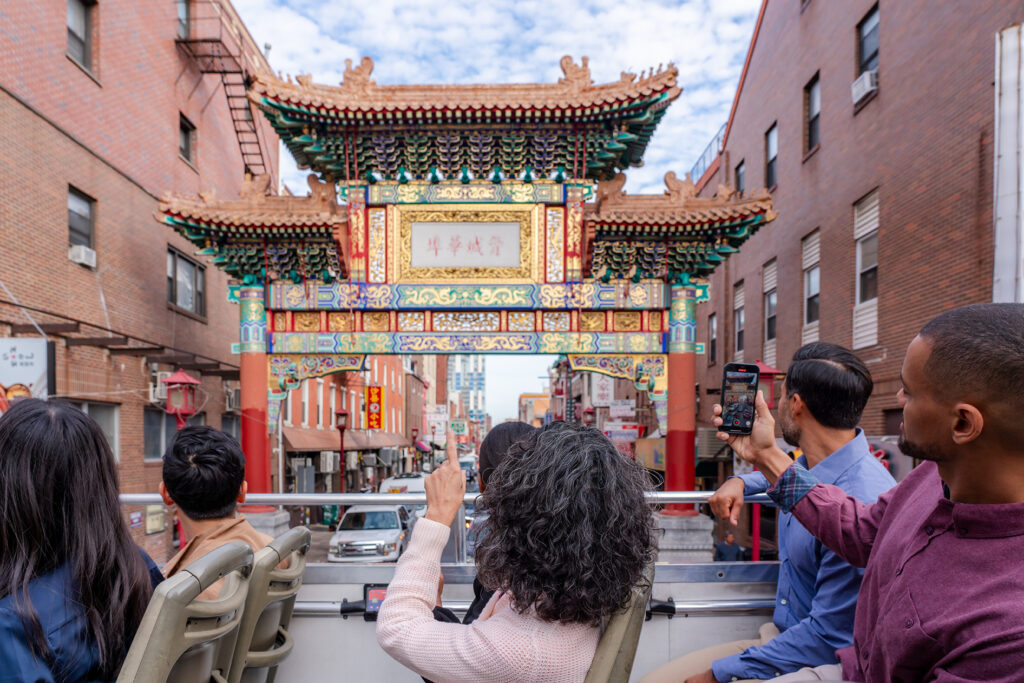 people on a tour bus photograph the Chinatown arch