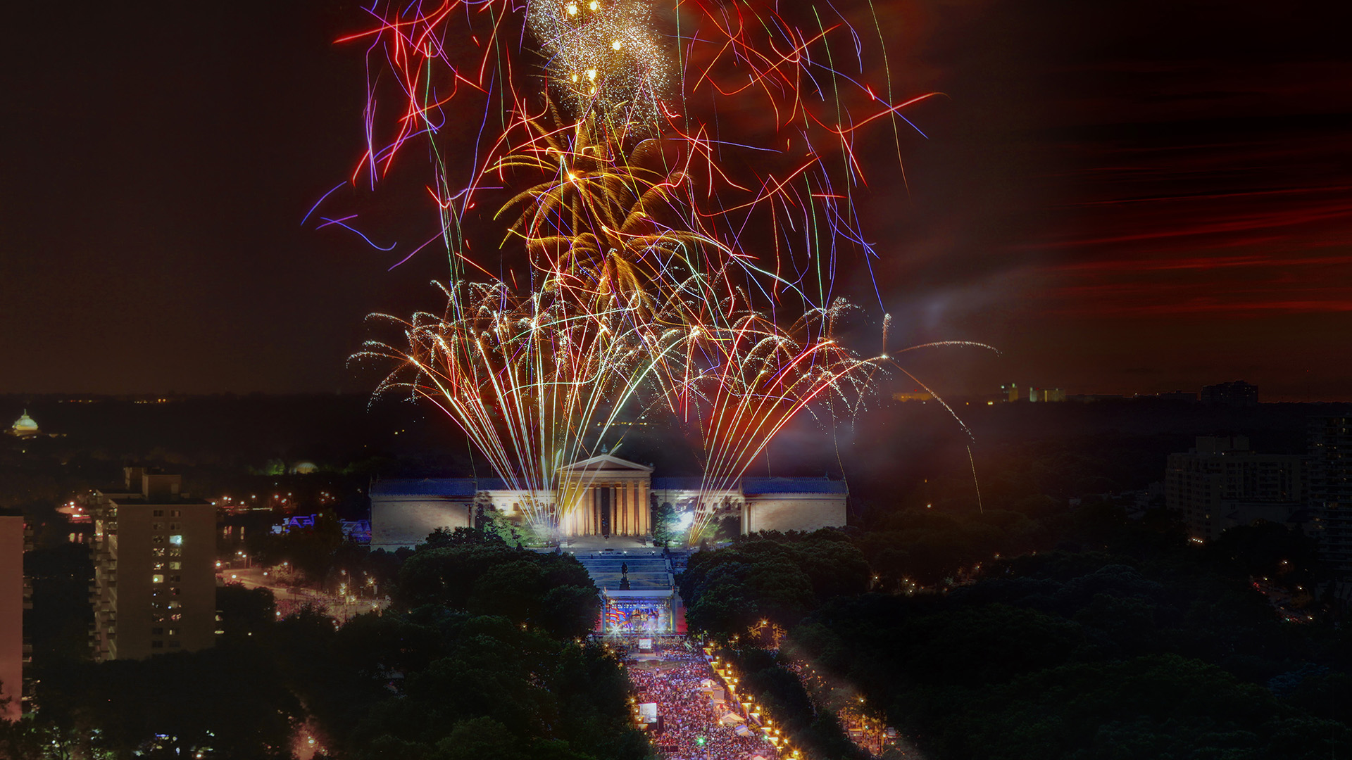 A huge fireworks display over the Philadelphia Museum of art. The Parkway is full of people and lights.