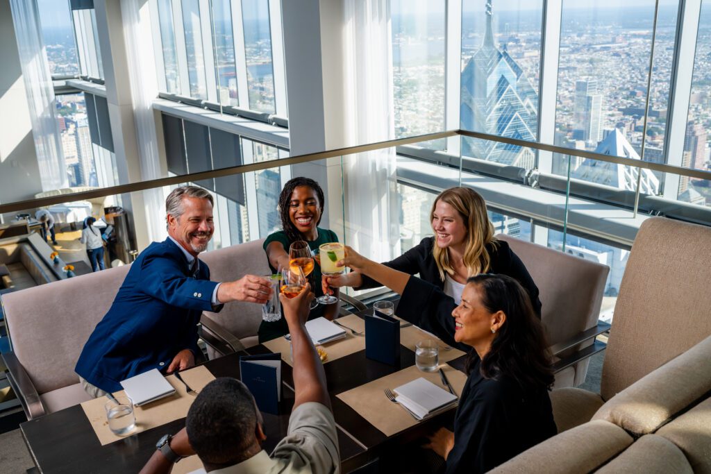 A business group cheers drinks at at table at SkyHigh on the 60th floor of the Comcast Center.
