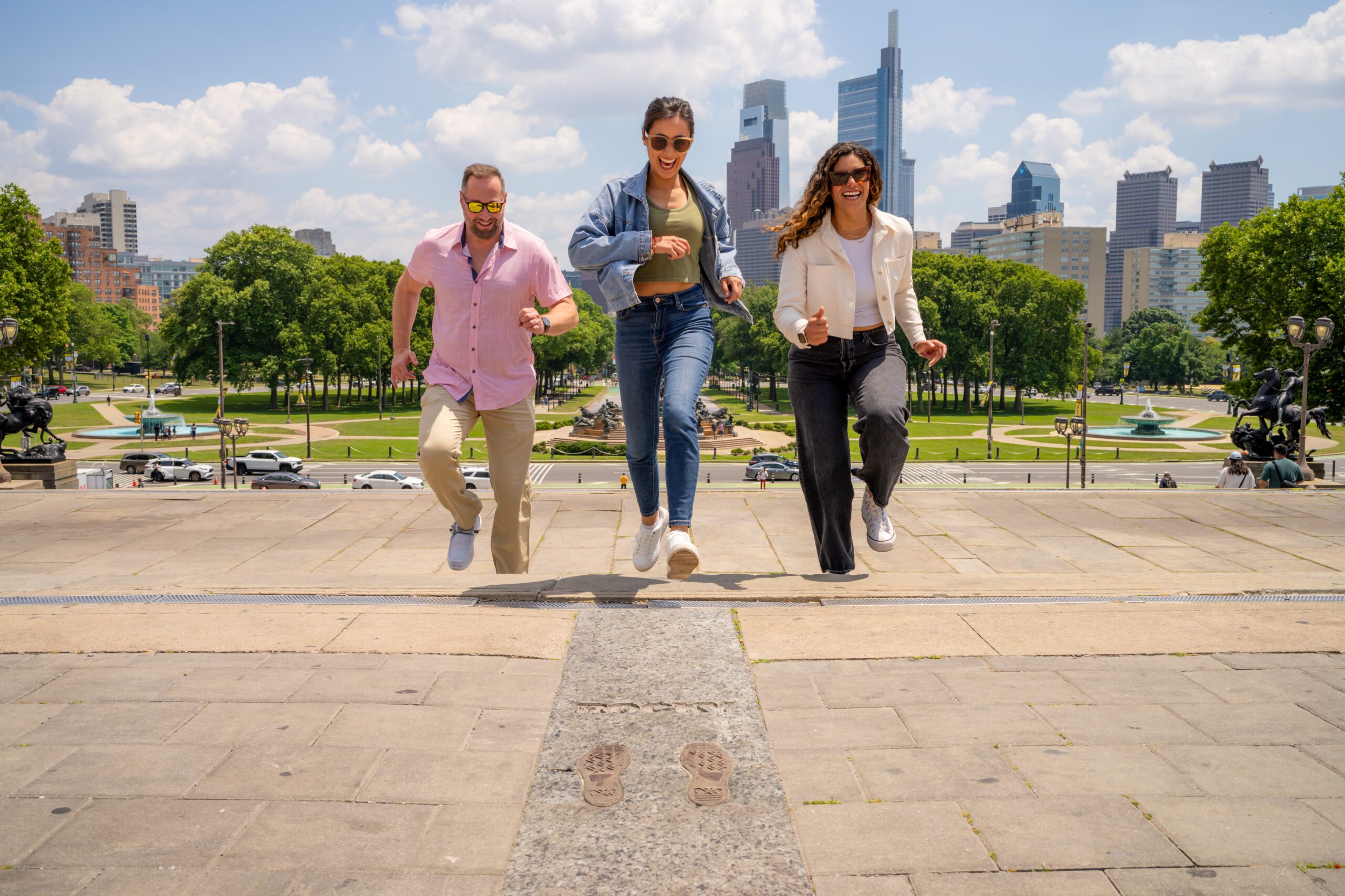 A group of three people run up the Rocky Steps, towards the camera.