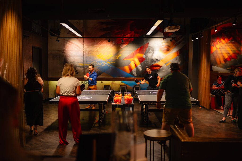 Four people play ping pong at two tables at SPiN Phhiladelphia.