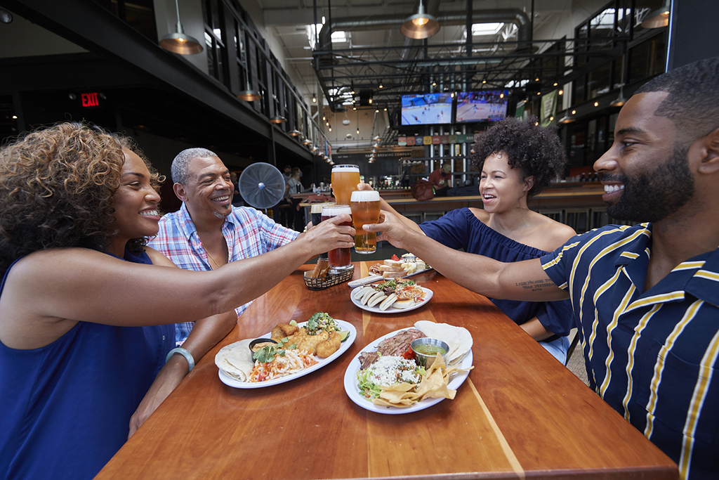 A group of people cheers beers inside a brewery.