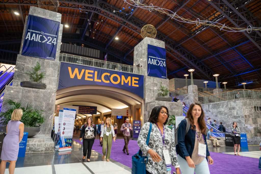 A welcome sign for AAIC 2024 attendees in the grand hall of the Pennsylvania Convention Center.