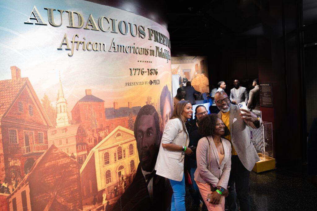 A group taking a selfie in front of a display at the African American Museum in Philadelphia.