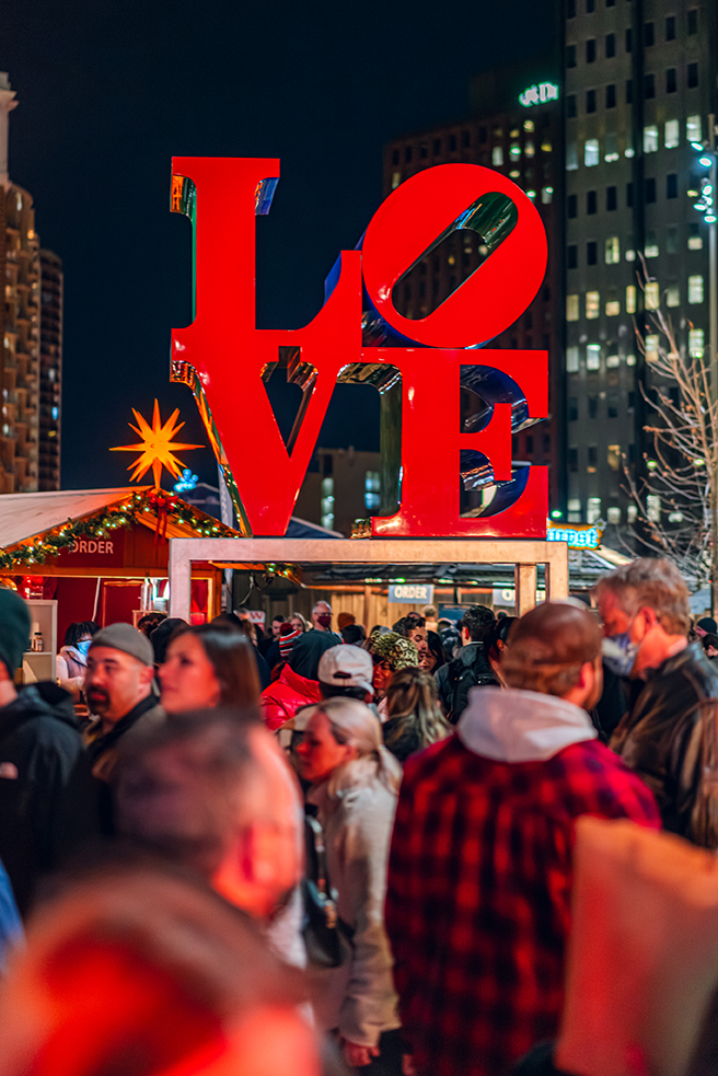 LOVE statue at Christmas Village with people walking around.