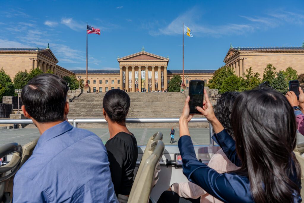 A group on a big bus tour take a photo of the Philadelphia Museum of Art.