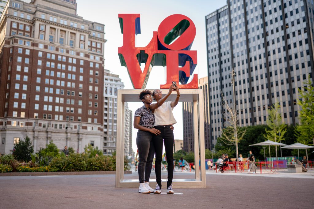 A couple takes a selfie in front of the LOVE statue in Philadelphia's LOVE Park.