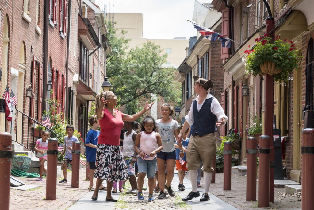 A group guide dressed in historic attire takes a group through Elfreth's Alley