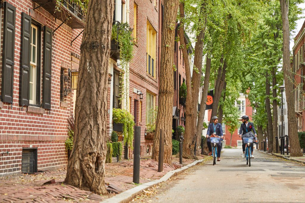 Two men riding Indego bikes along a street in Philadelphia.