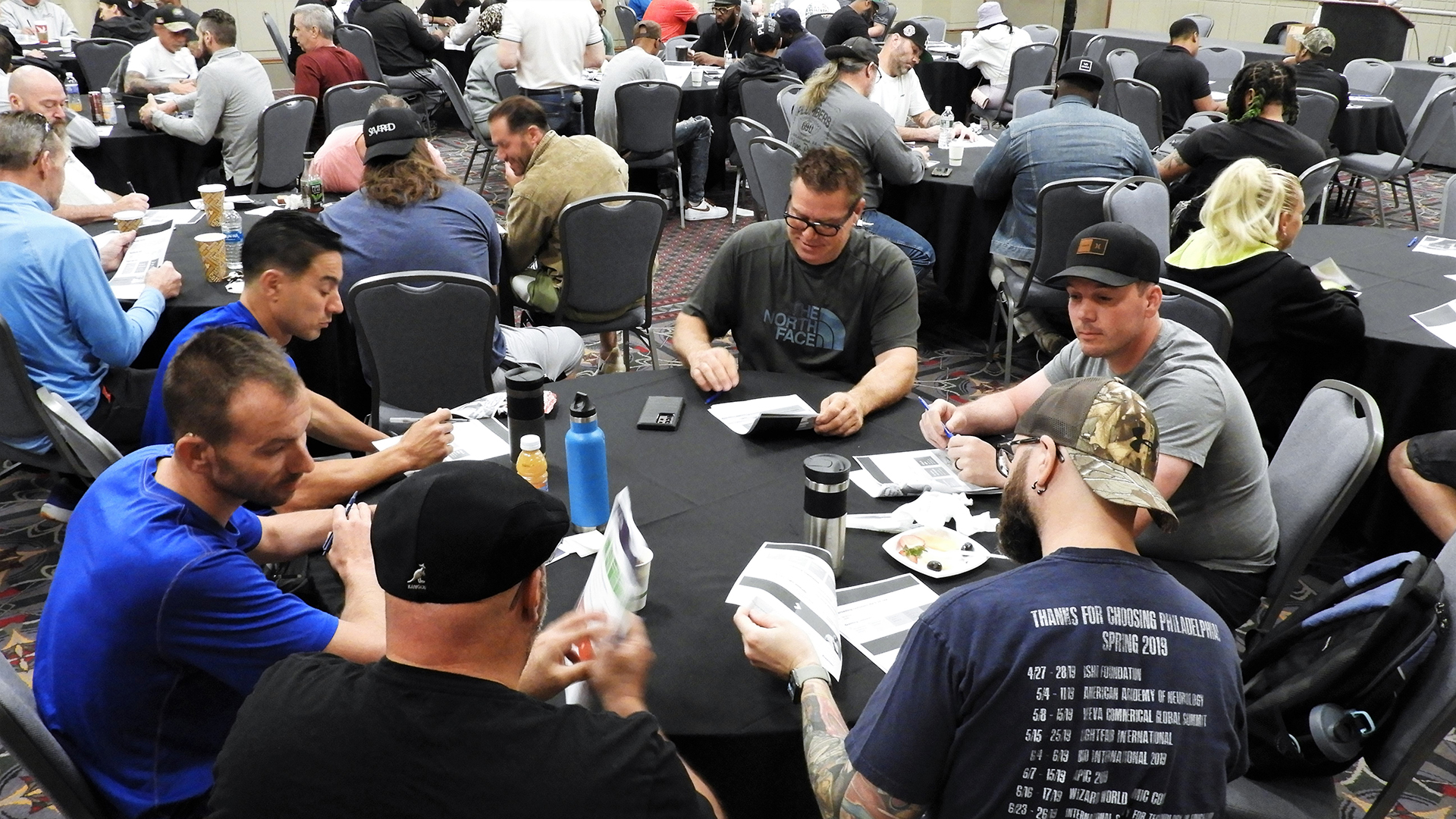 A group of people sit around a table in a training center.