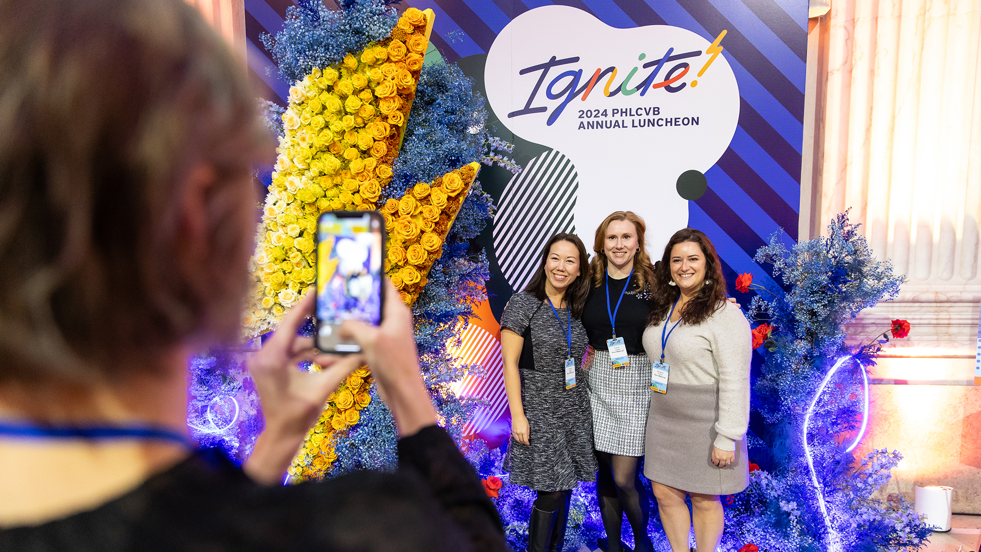 Three people pose for a photo in front of the Ignite Annual Luncheon step and repeat.