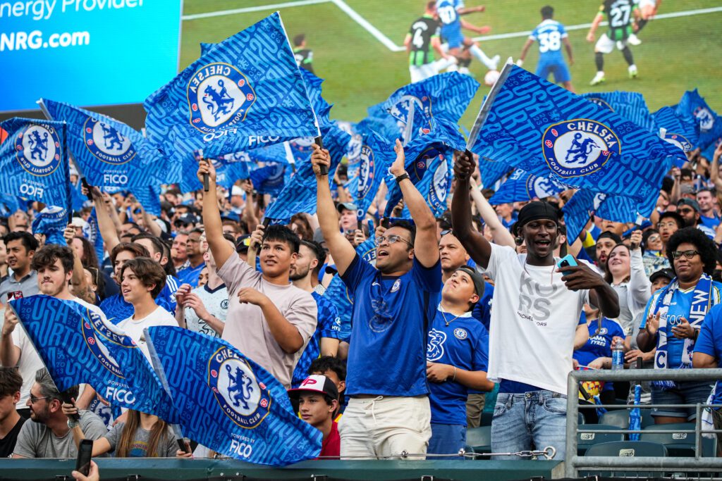 Chelsea F.C. fans stand with flags as they cheer on the team at Lincoln Financial Field. 