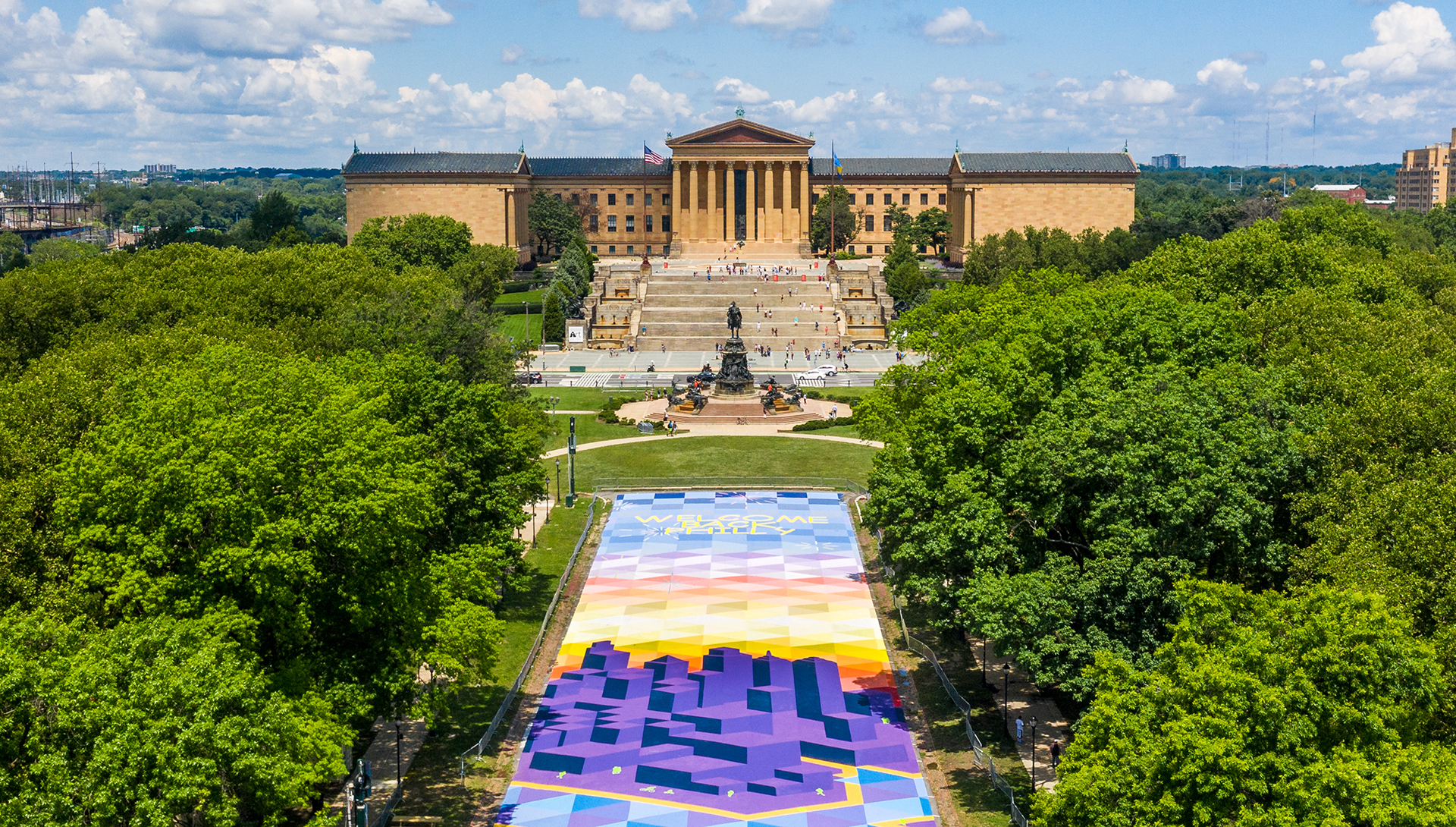 The Philadelphia Museum of art sits at the end of a parkway that is covered in a chalk drawing of the city and the words 