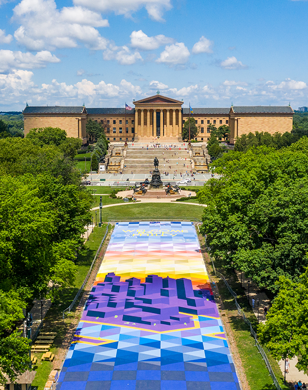 The Philadelphia Museum of art sits at the end of a parkway that is covered in a chalk drawing of the city and the words 